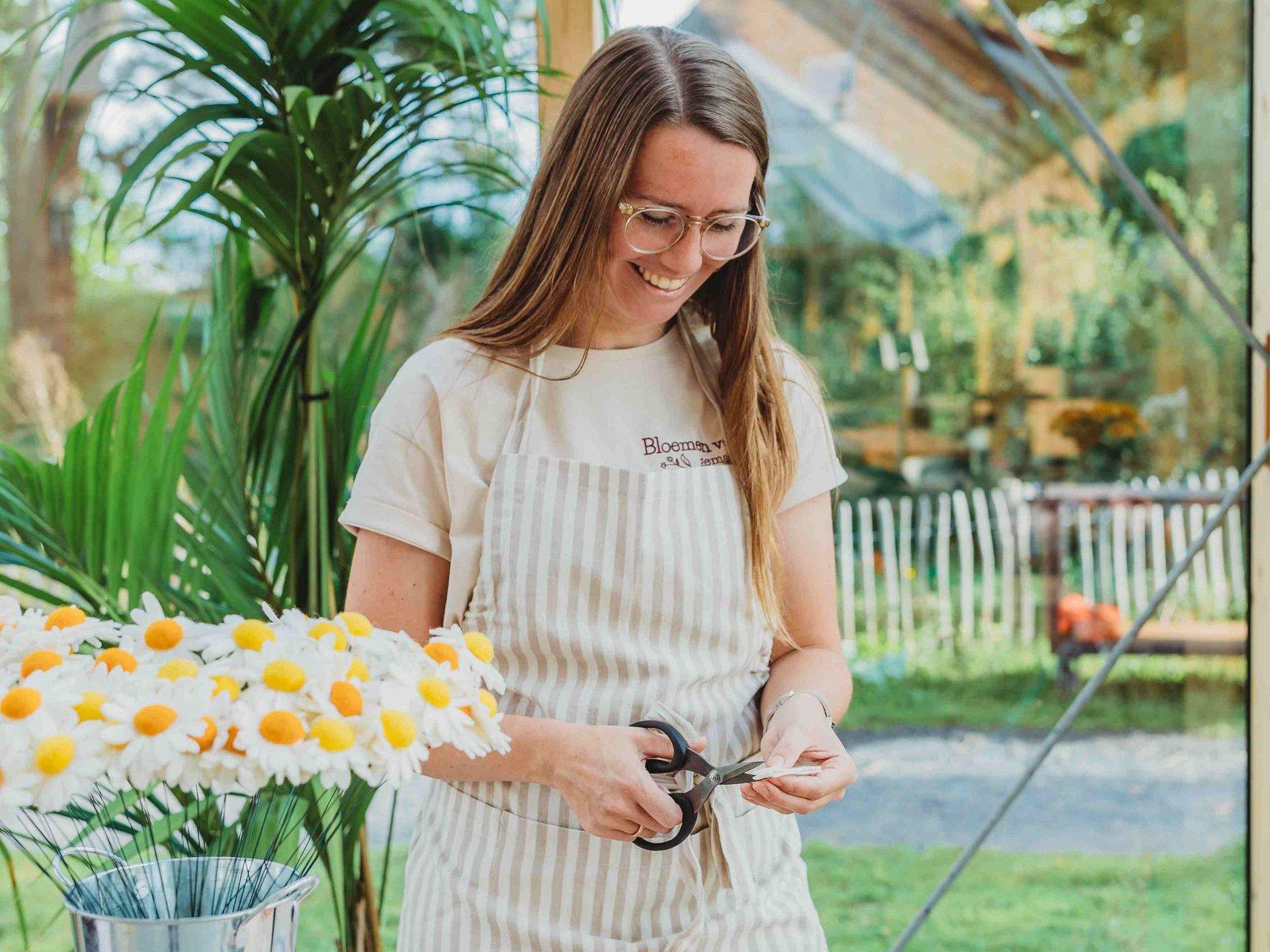Patricia met een schort voor knipt viltbloemen met een schaar.