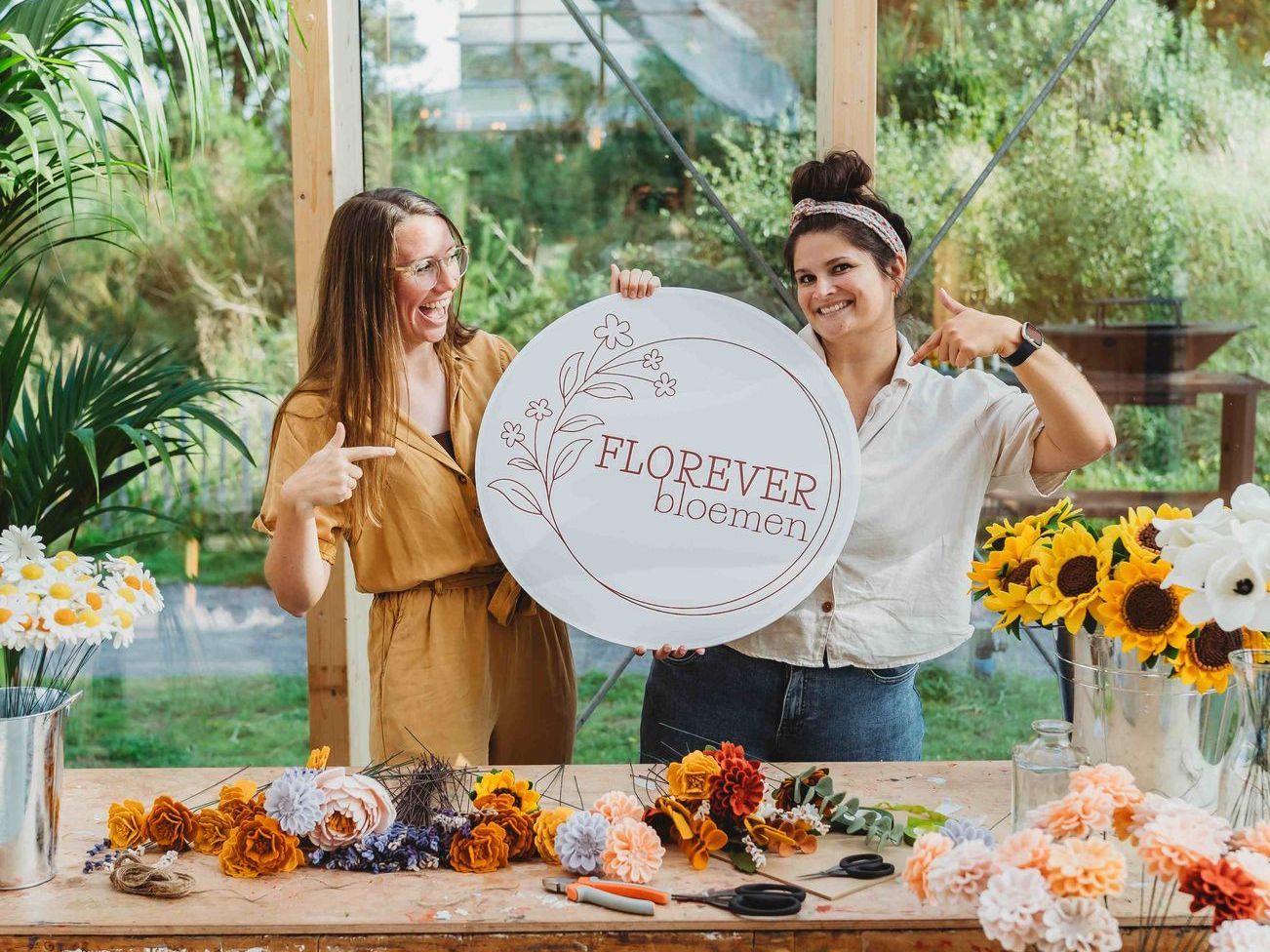 Nathalie en Patricia houden een bord vast met het logo van florever bloemen