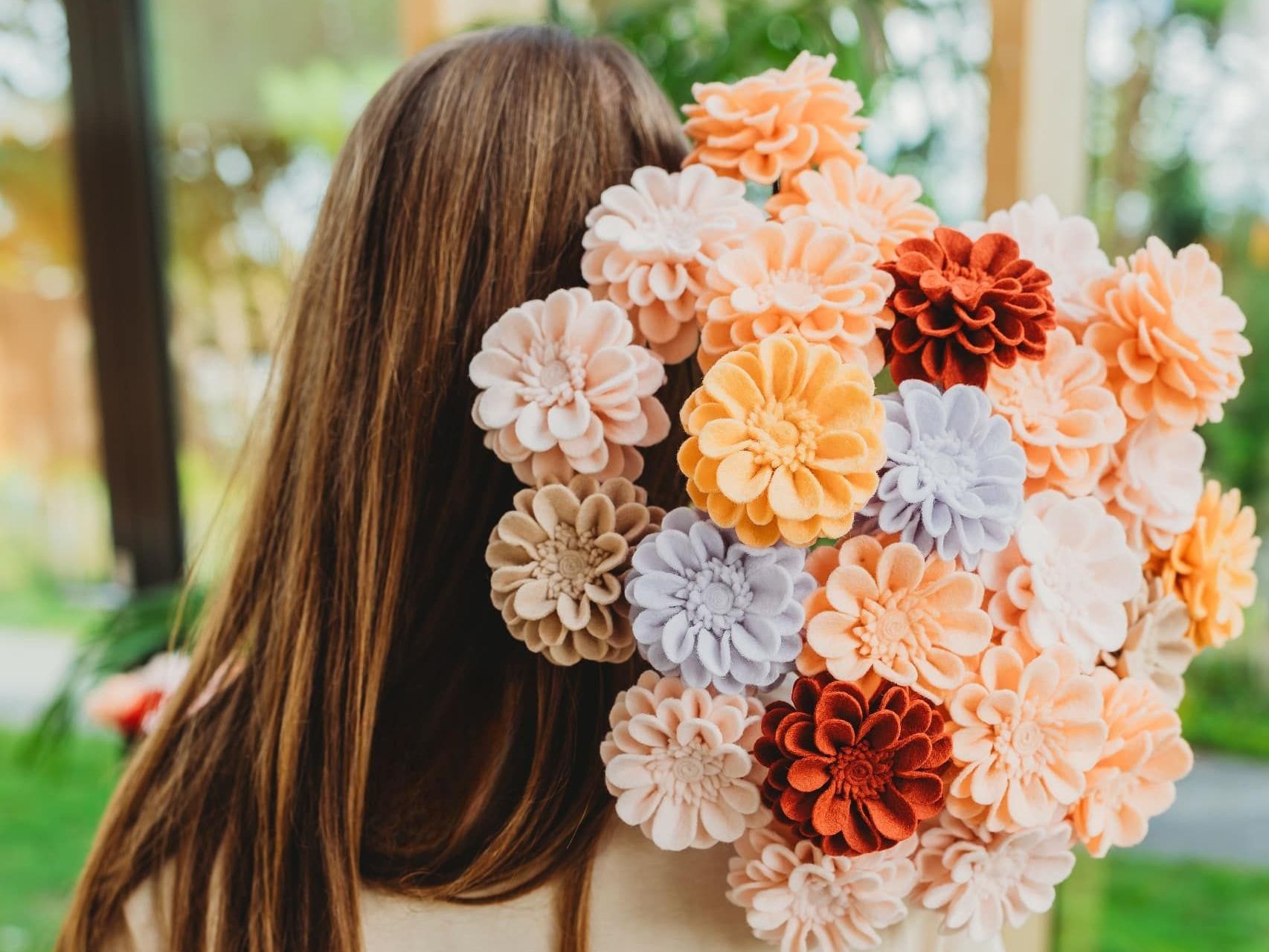 Patricia houdt een boeket viltbloemen achter haar rug, heel veel dahlia's