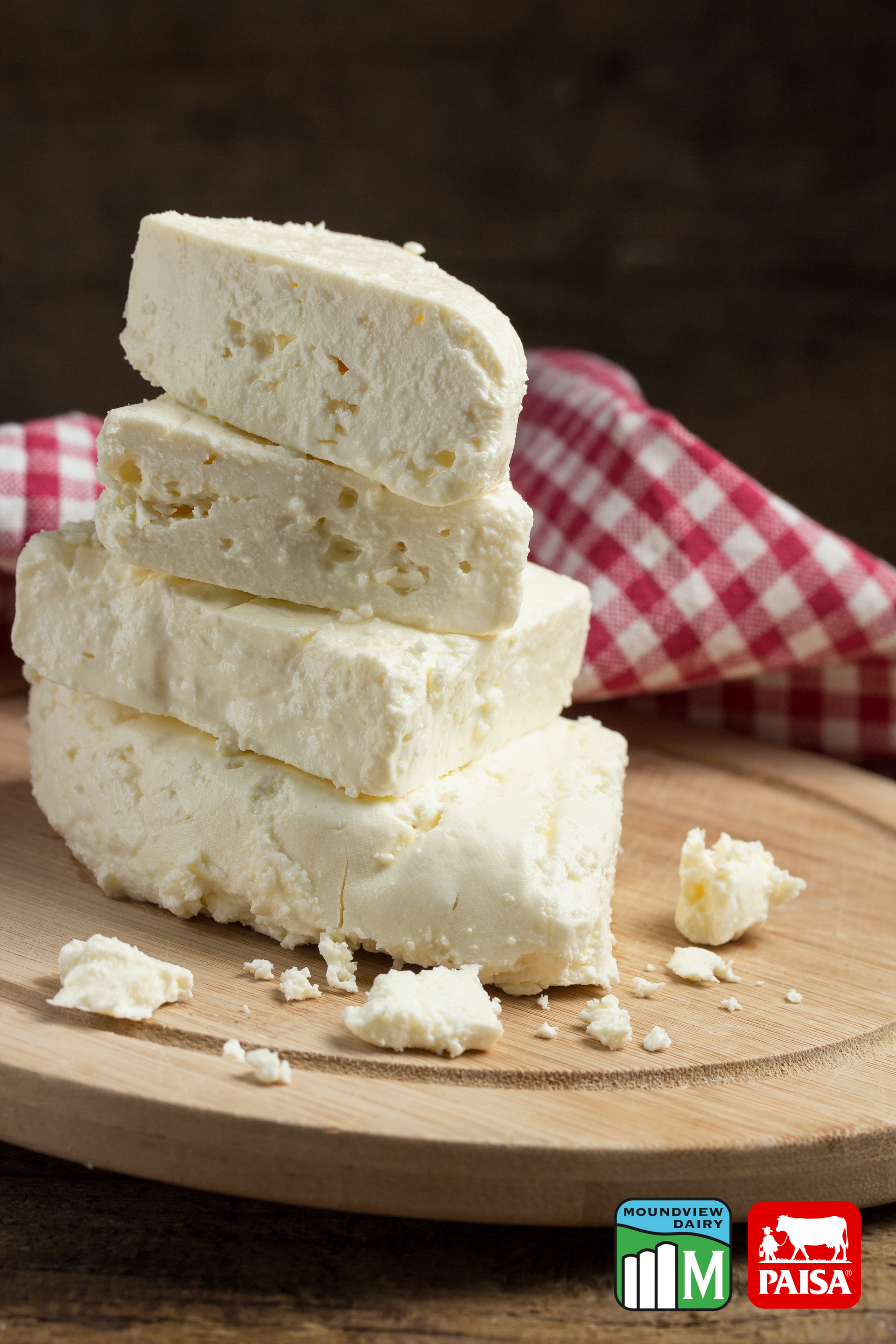 A wooden cutting board with sliced cheese and avocado on it