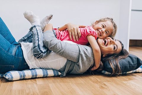 Mother and daughter hug on floor.