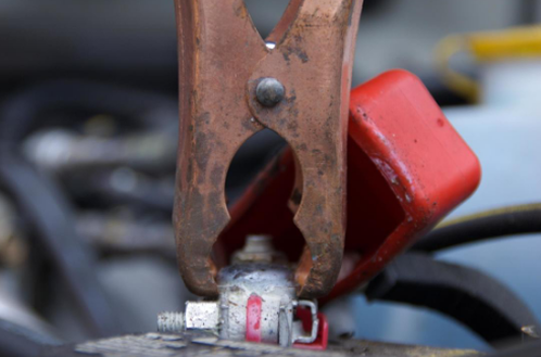 A close up of a pair of copper clamps attached to a car battery.