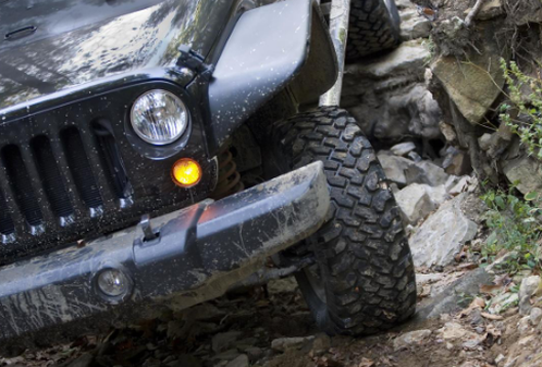 A black jeep is driving down a rocky road.