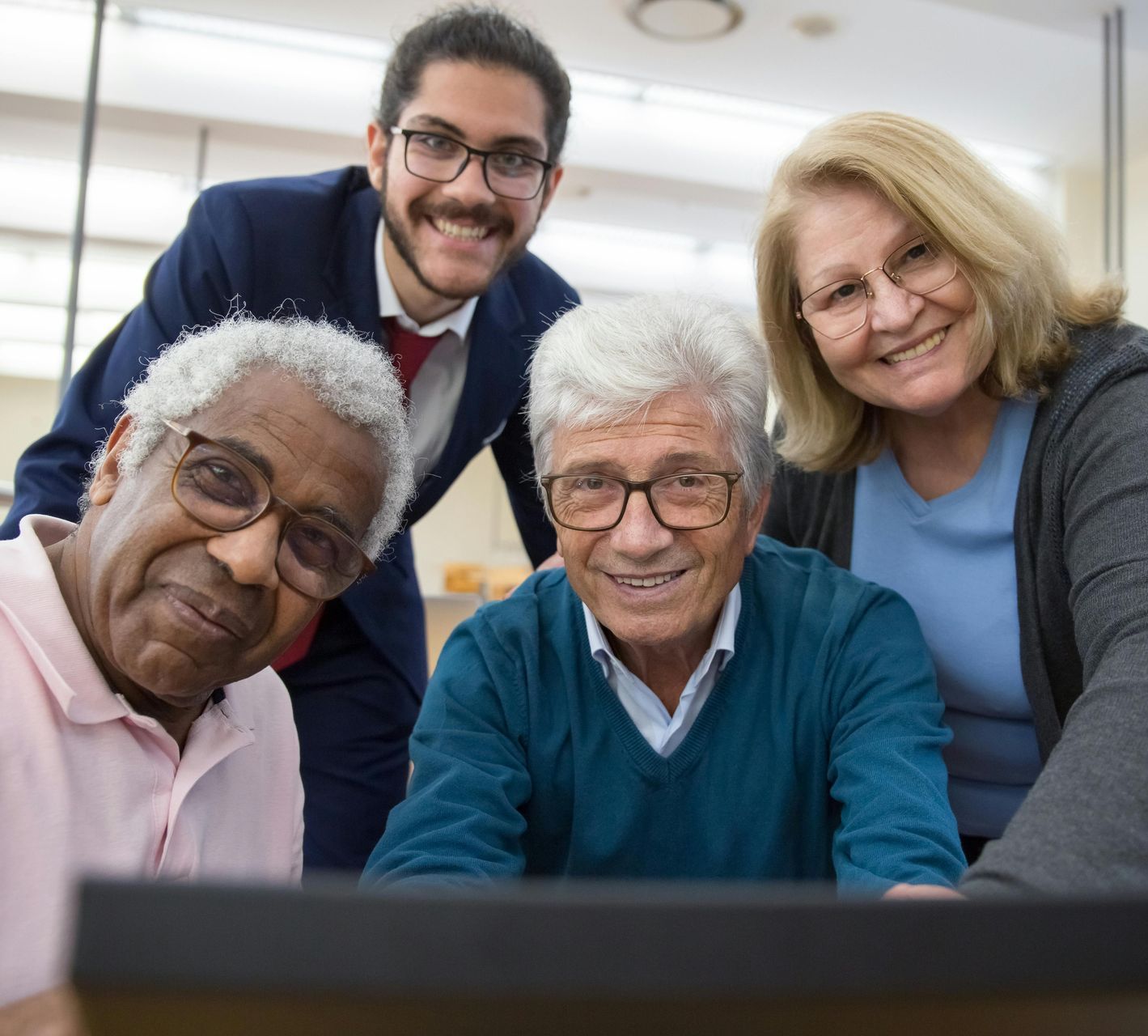A group of people are posing for a picture in front of a laptop computer.