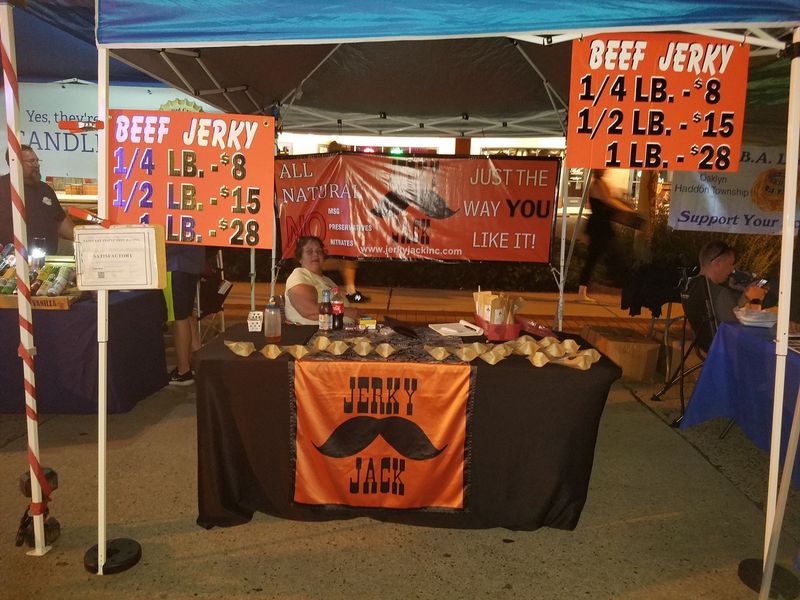 A large room filled with tables and signs advertising jerky