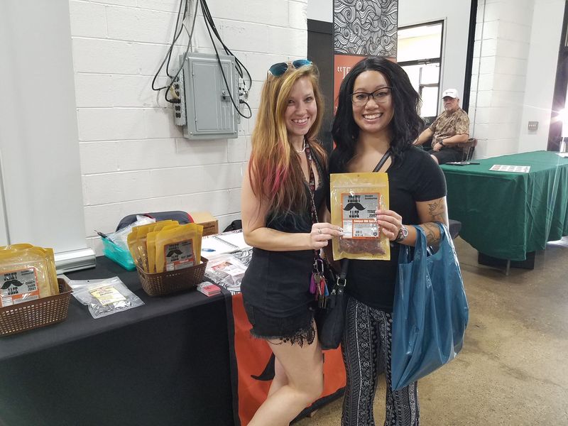 Two women are standing next to each other holding bags of food.