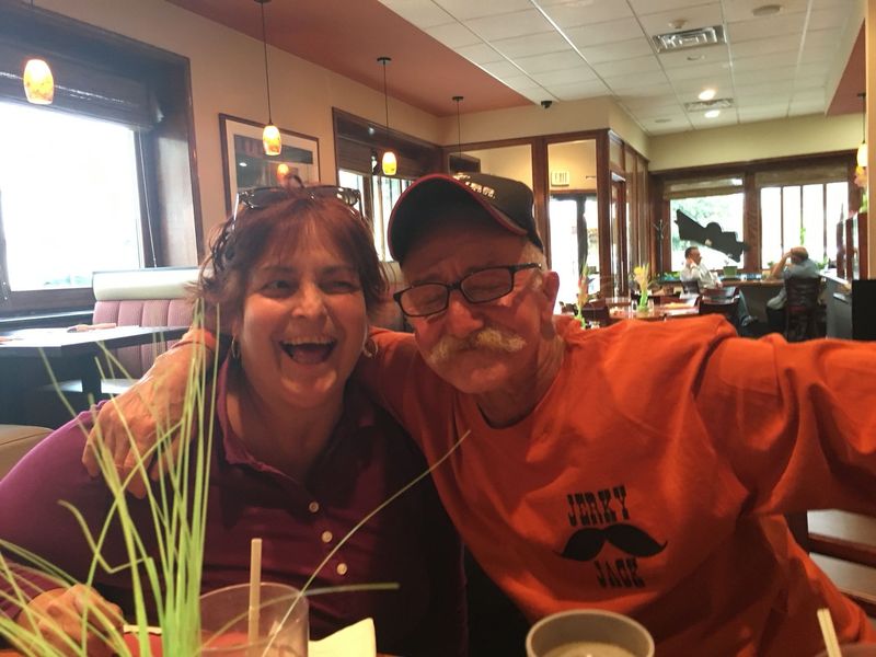 A man and a woman are posing for a picture in a restaurant.