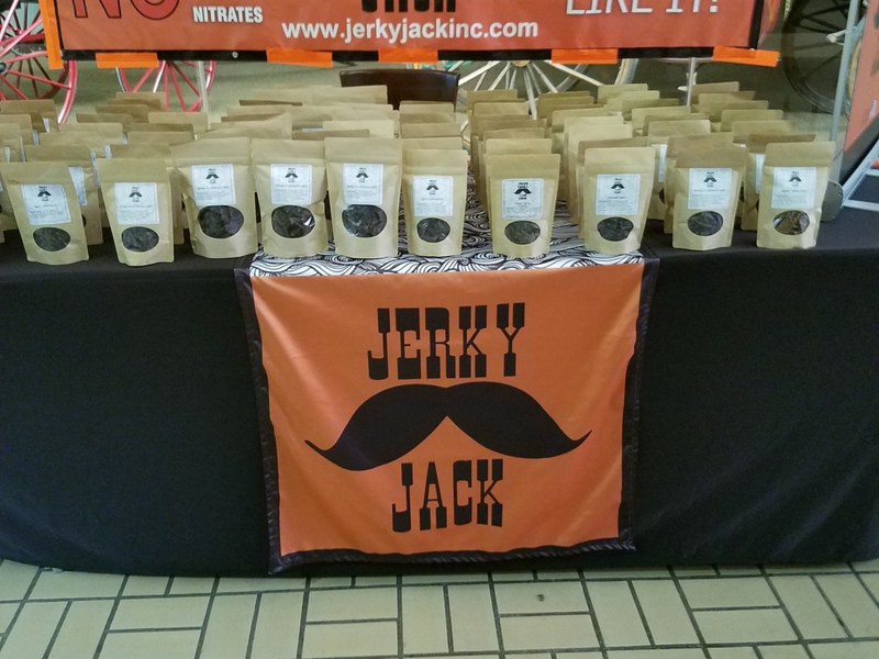 A table with bags of jerky and an orange sign that says jerky jack