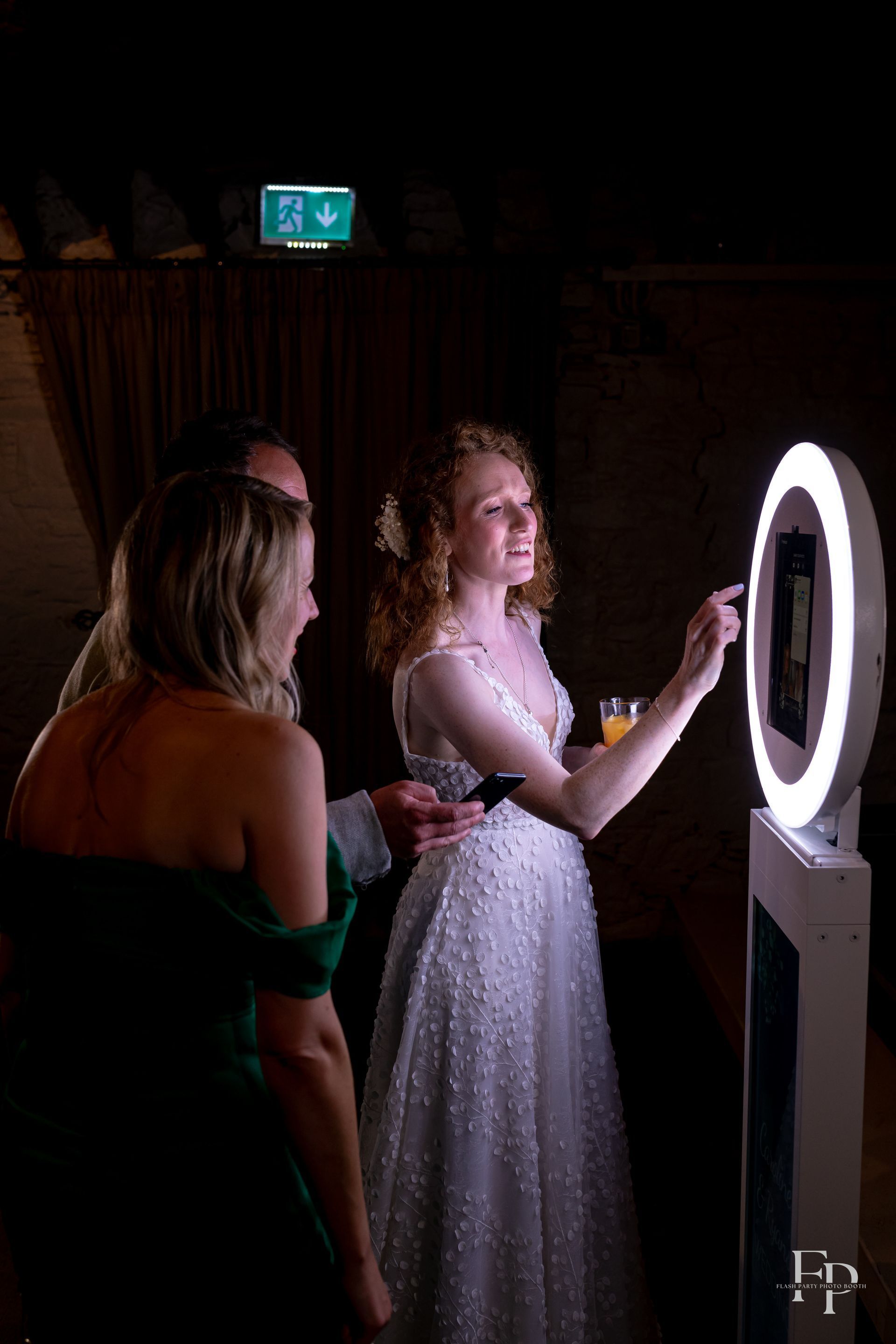 A woman in a white dress looking at a round light of a Selfie Photo Booth.