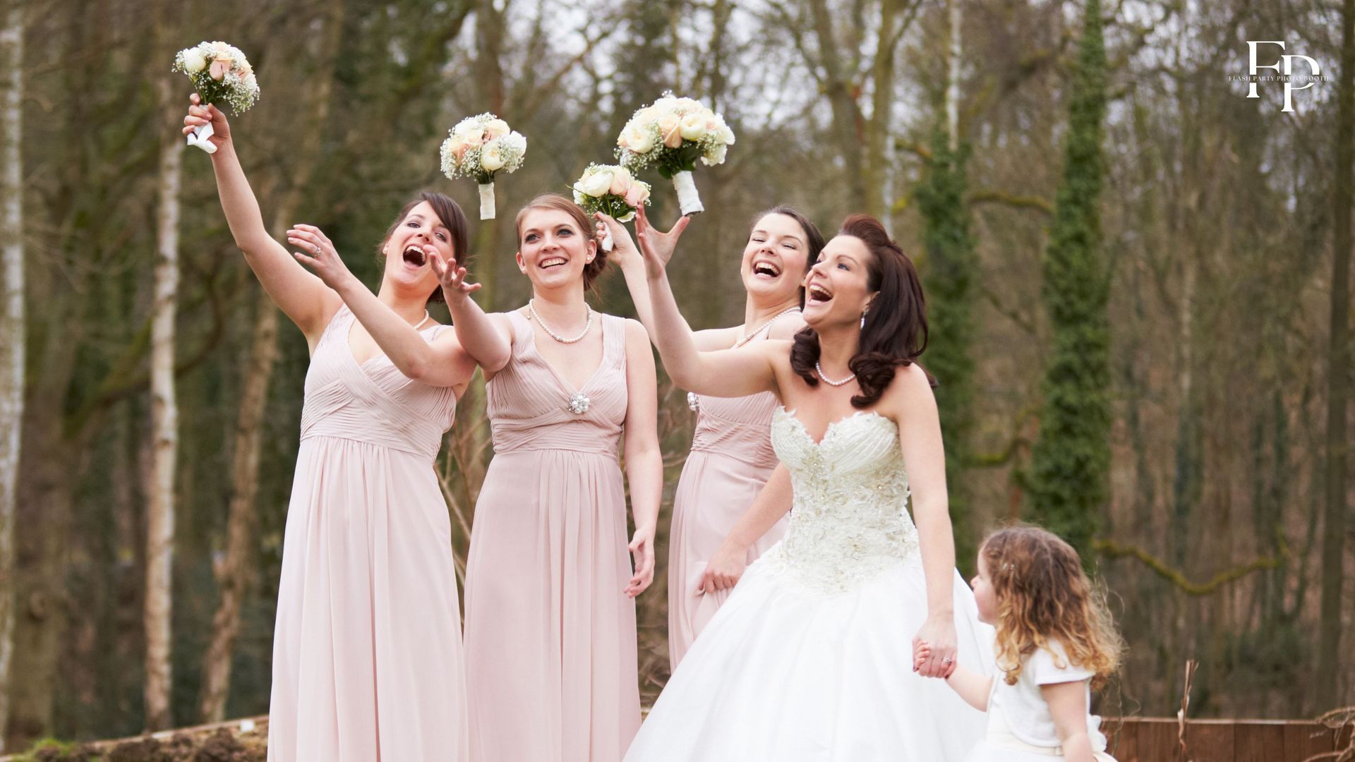 Bride and bridesmaids in Atlanta playfully toss their bouquets in the air.
