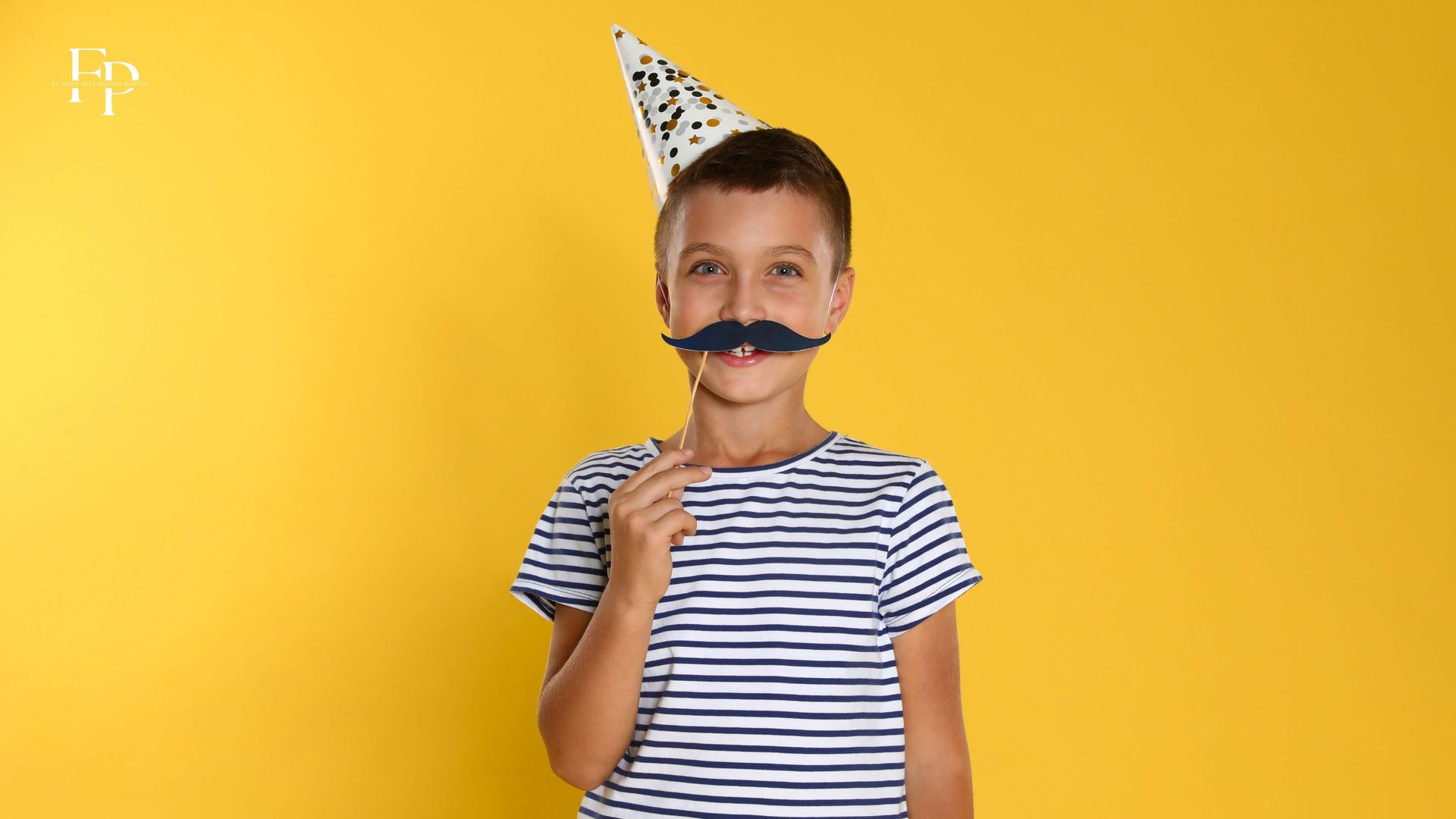A boy enjoys playful moments with a mustache prop at the Flash Party photo booth during a birthday party in Dallas.