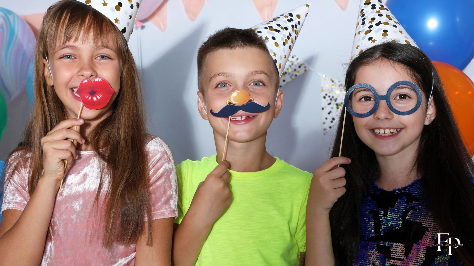 Three kids having fun while holding their props at a birthday party in Atlanta.