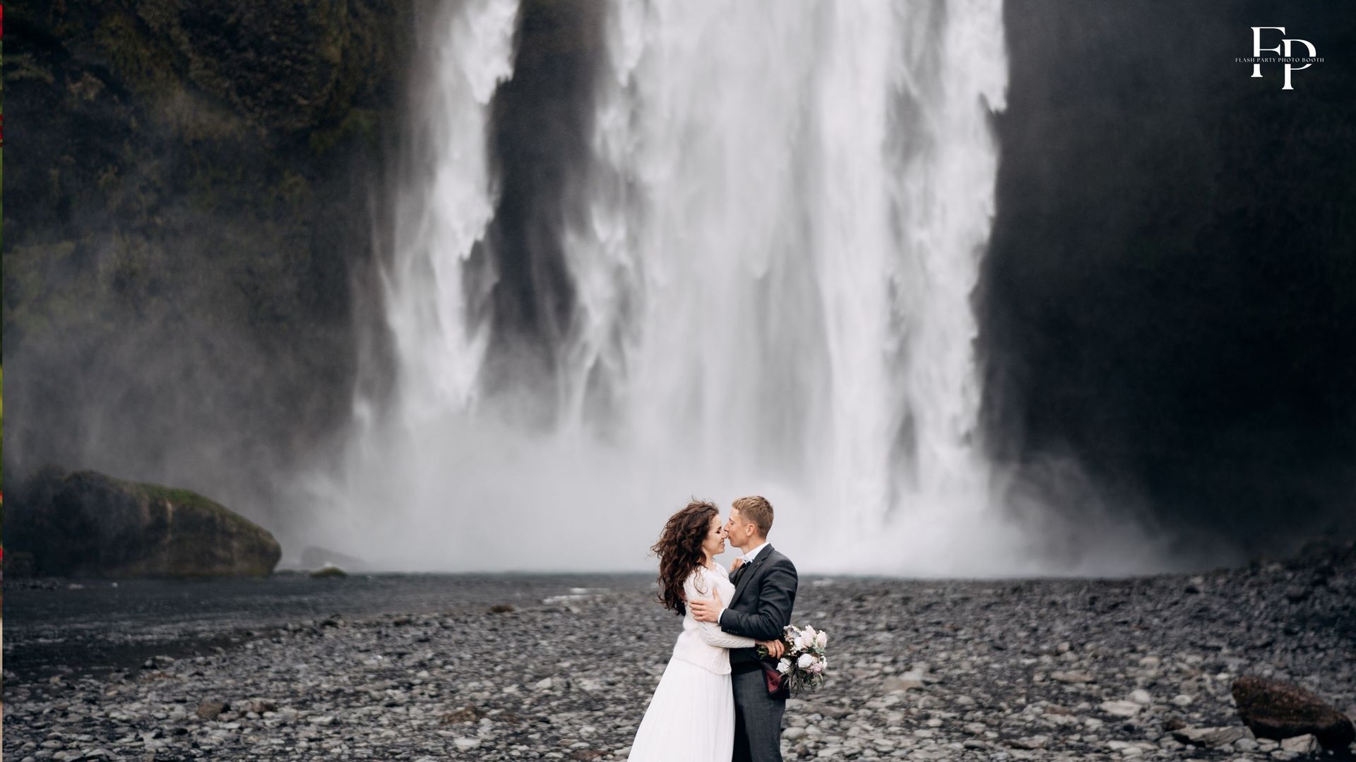 Bride and groom standing before a waterfall