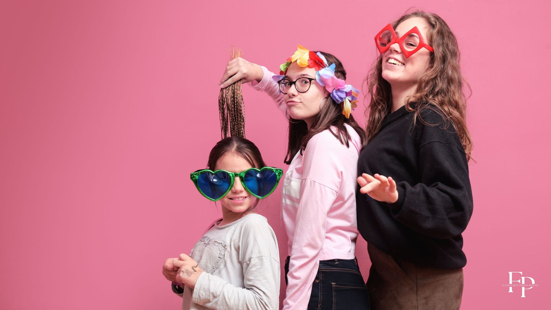Sisters make silly poses with Flash Party's photo booth props during a birthday party.