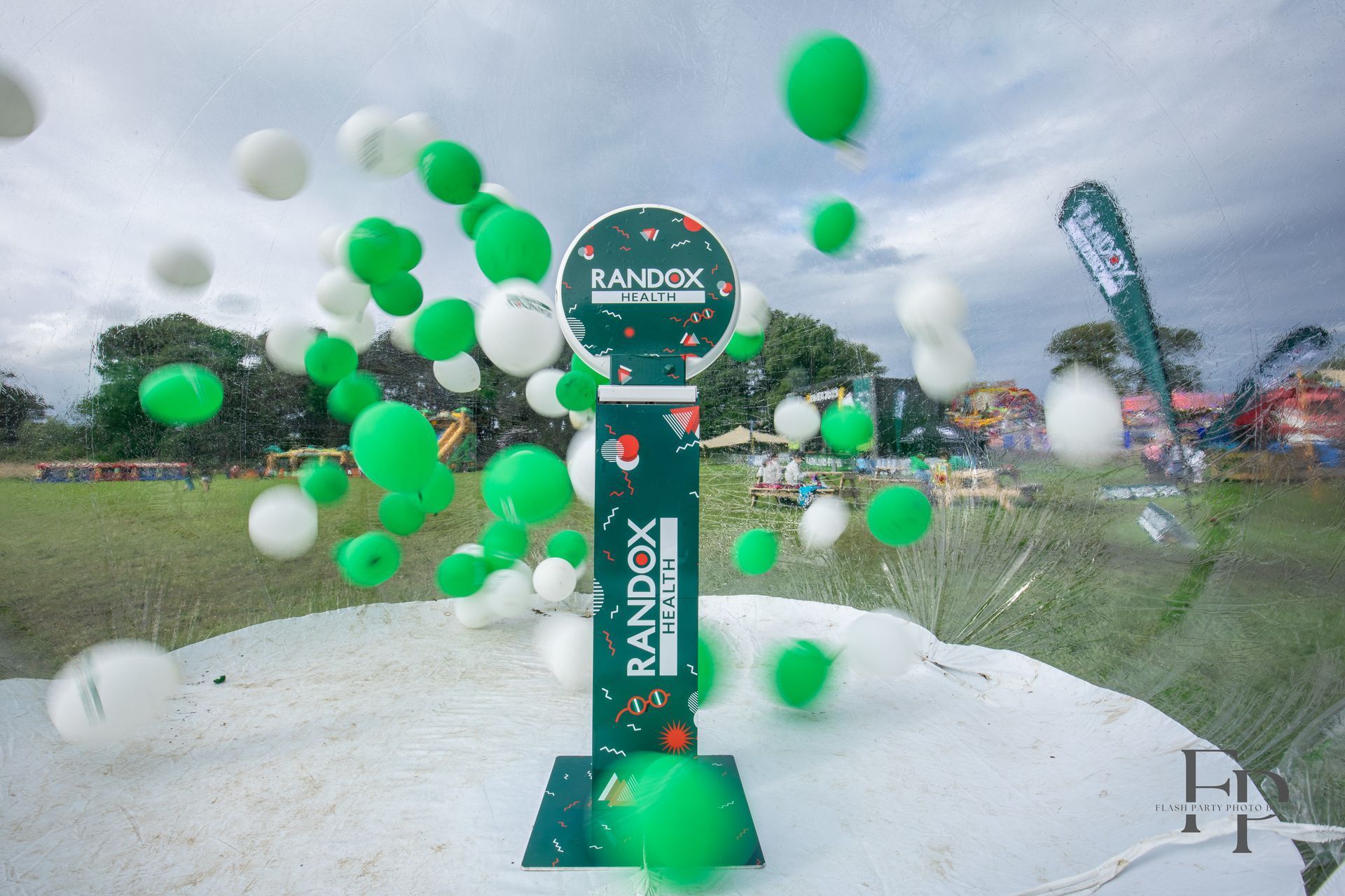 Selfie Photo Booth set up outdoors with green and white balloons in the air.