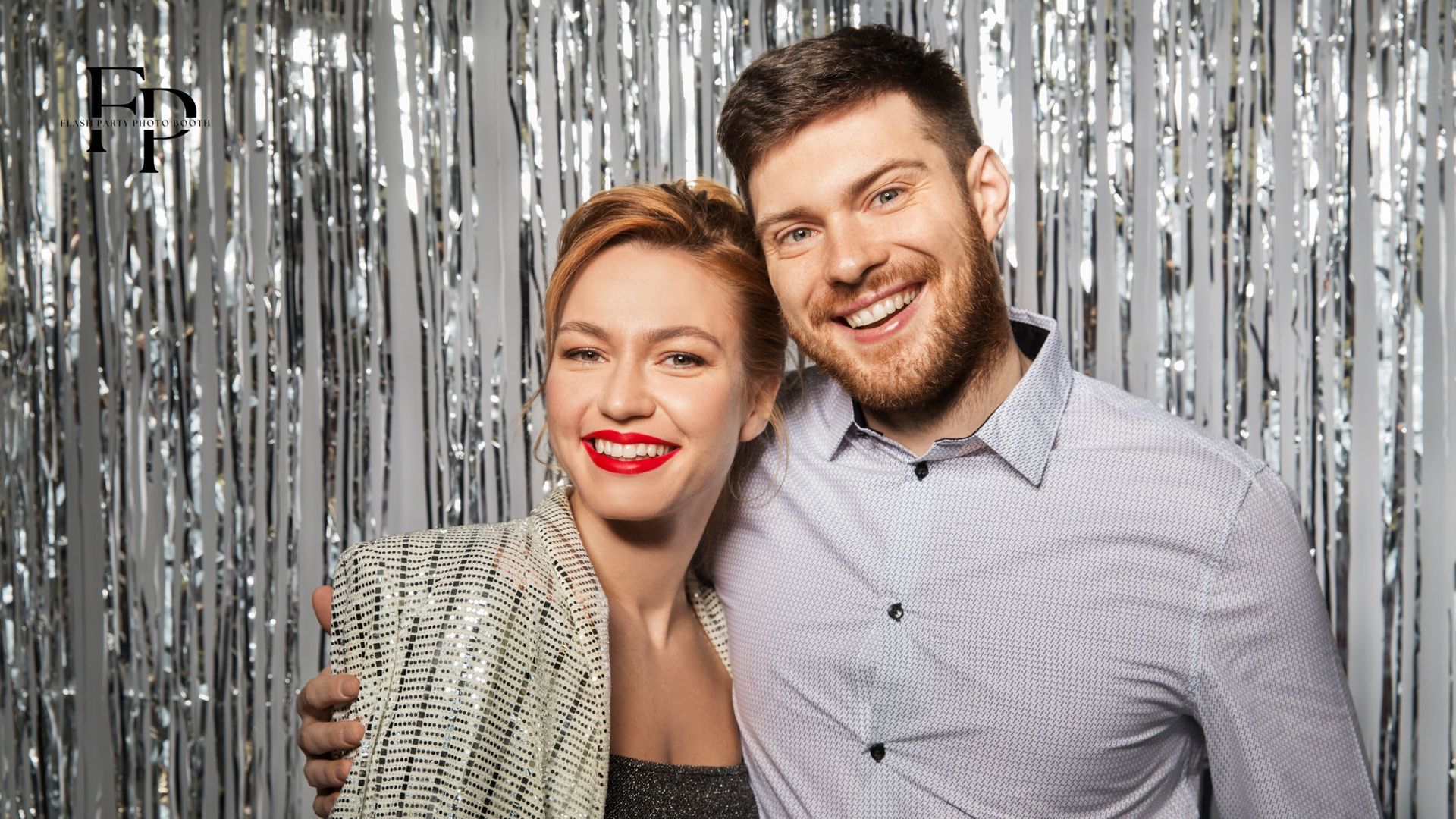 A man and woman posing at a sparkly photo booth backdrop during a graduation party in Houston