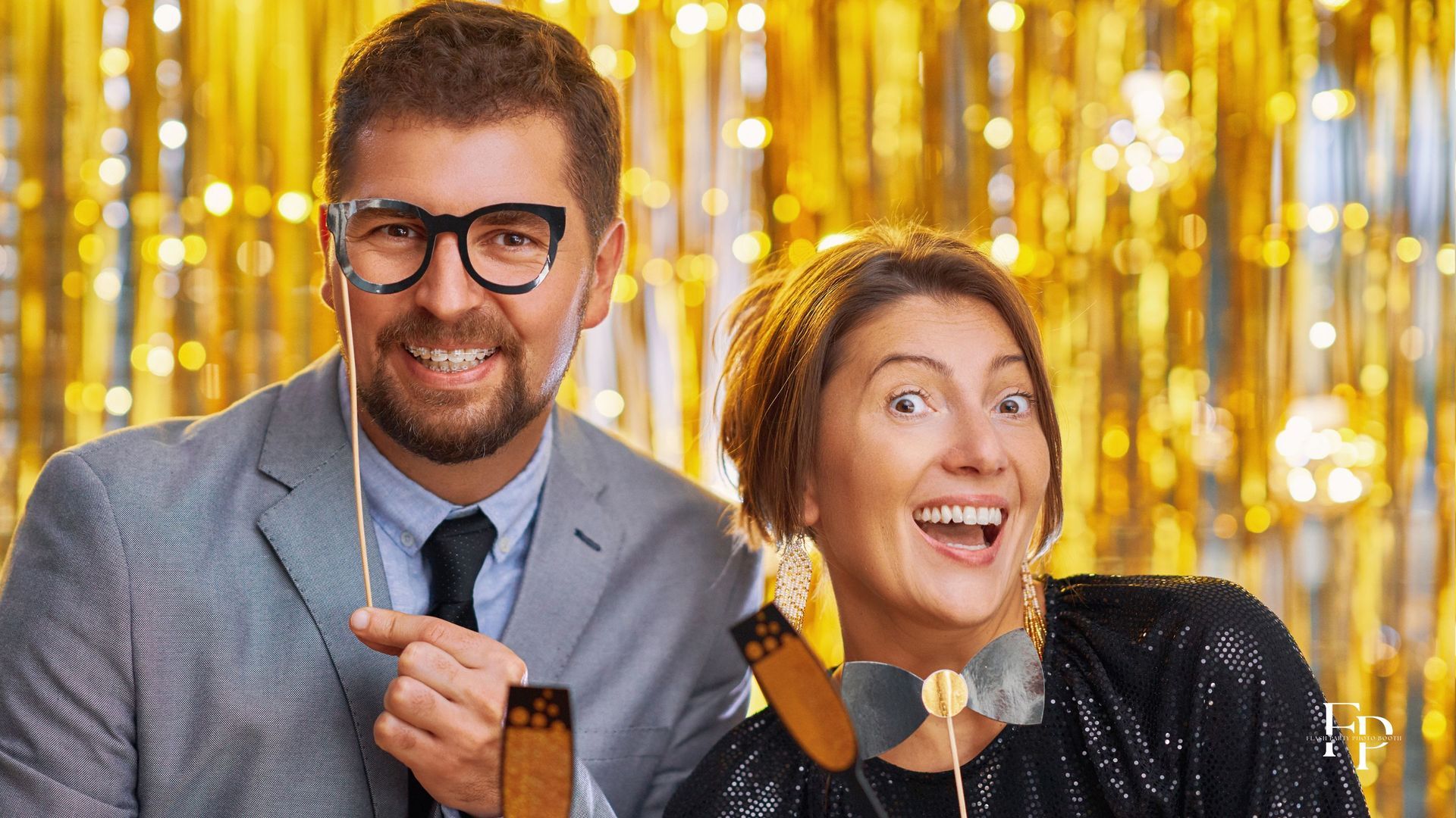 Two friends before a photo booth rental with a golden backdrop to celebrate in Manor
