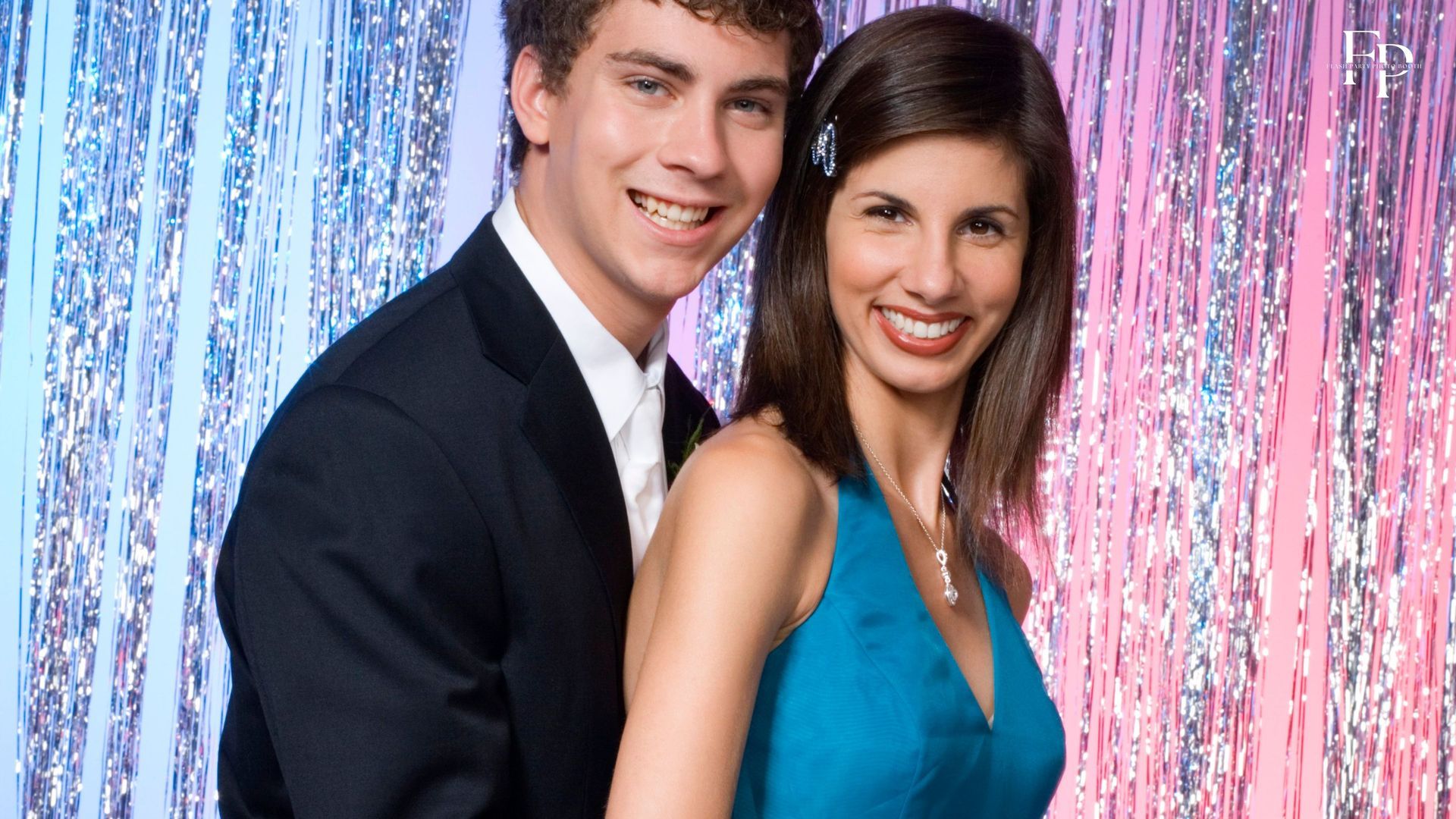 A man with his prom date posing at a sparkling photo booth backdrop for their prom party in Manor