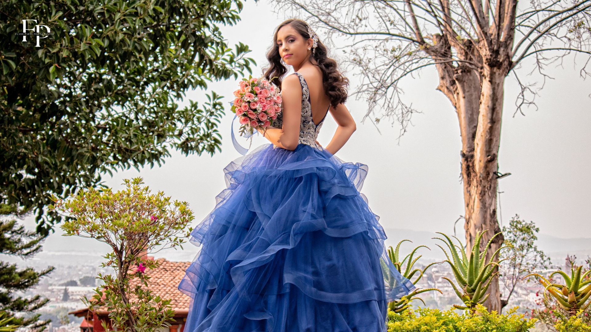 The celebrant in a beautiful blue  gown, holding a bouquet and posing at her quinceanera venue in North Austin