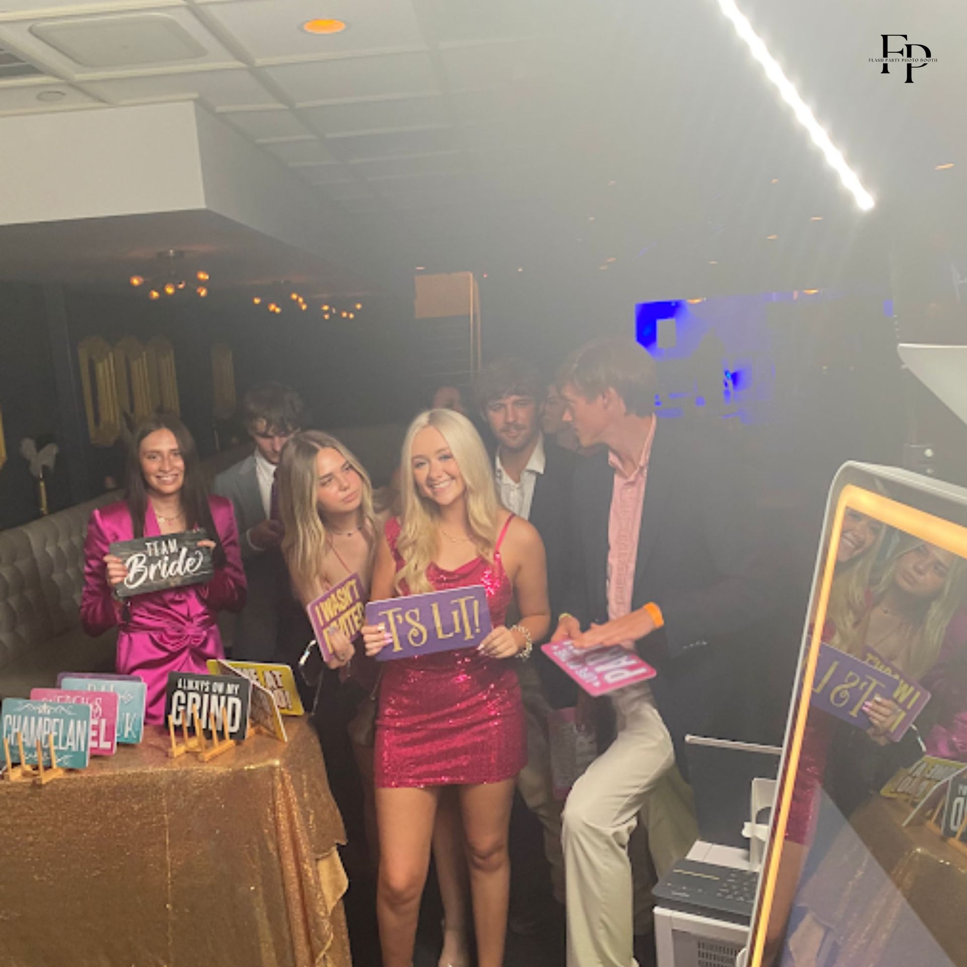 A lively party scene with a group of people cheerfully posing for a photo with the Mirror Photo Booth.