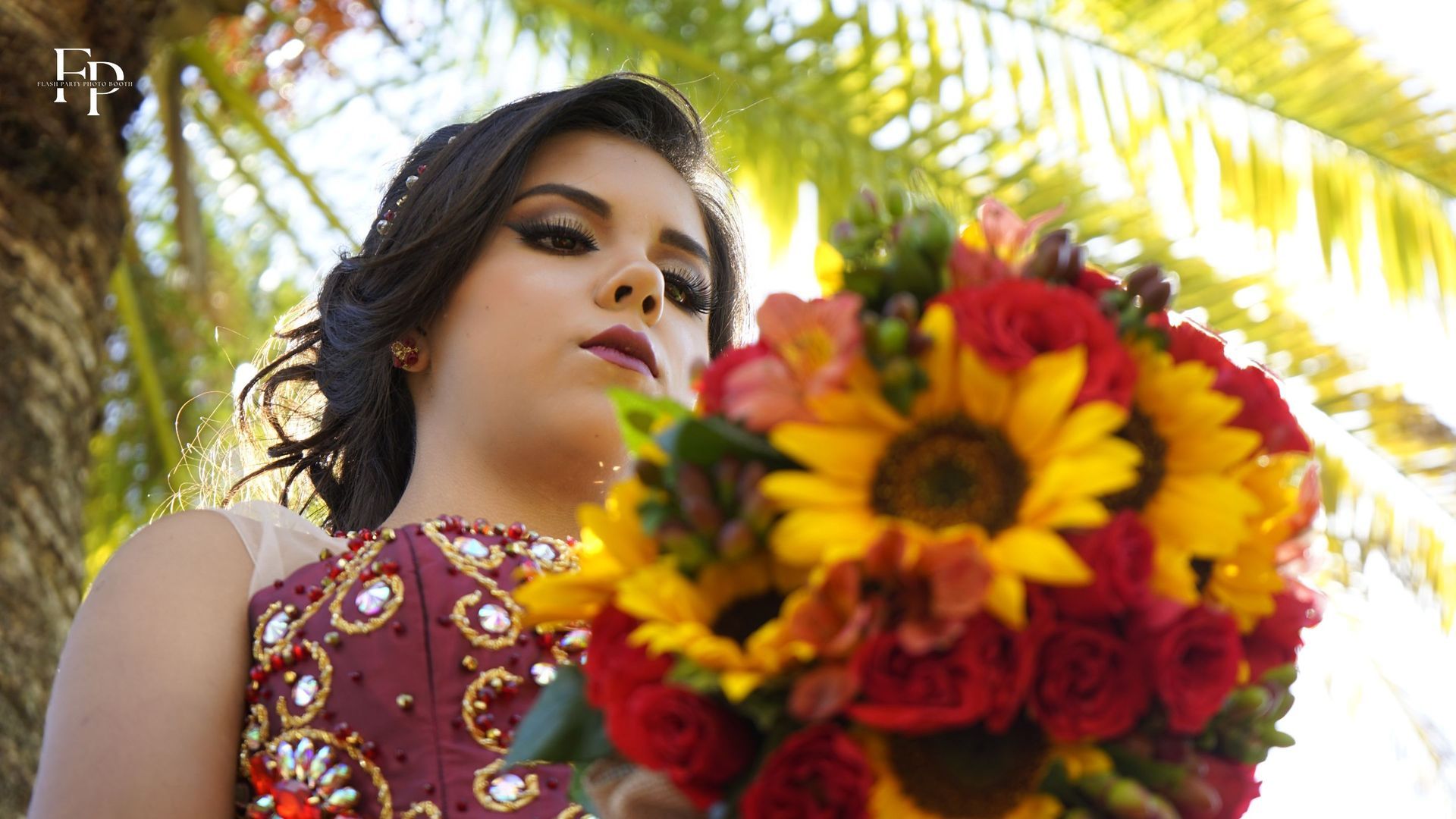 Surrounded by the vibrant colors and sweet scents of fresh blooms, the celebrant holds a bouquet of flowers at her quinceañera in DFW, her radiant smile illuminating the room.