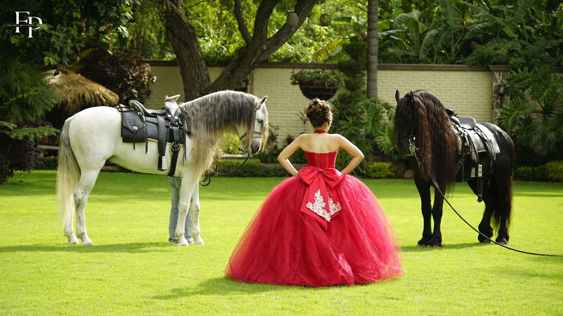 A celebrant in a stunning red gown striking a pose with horses for a photo shoot for her quinceanera