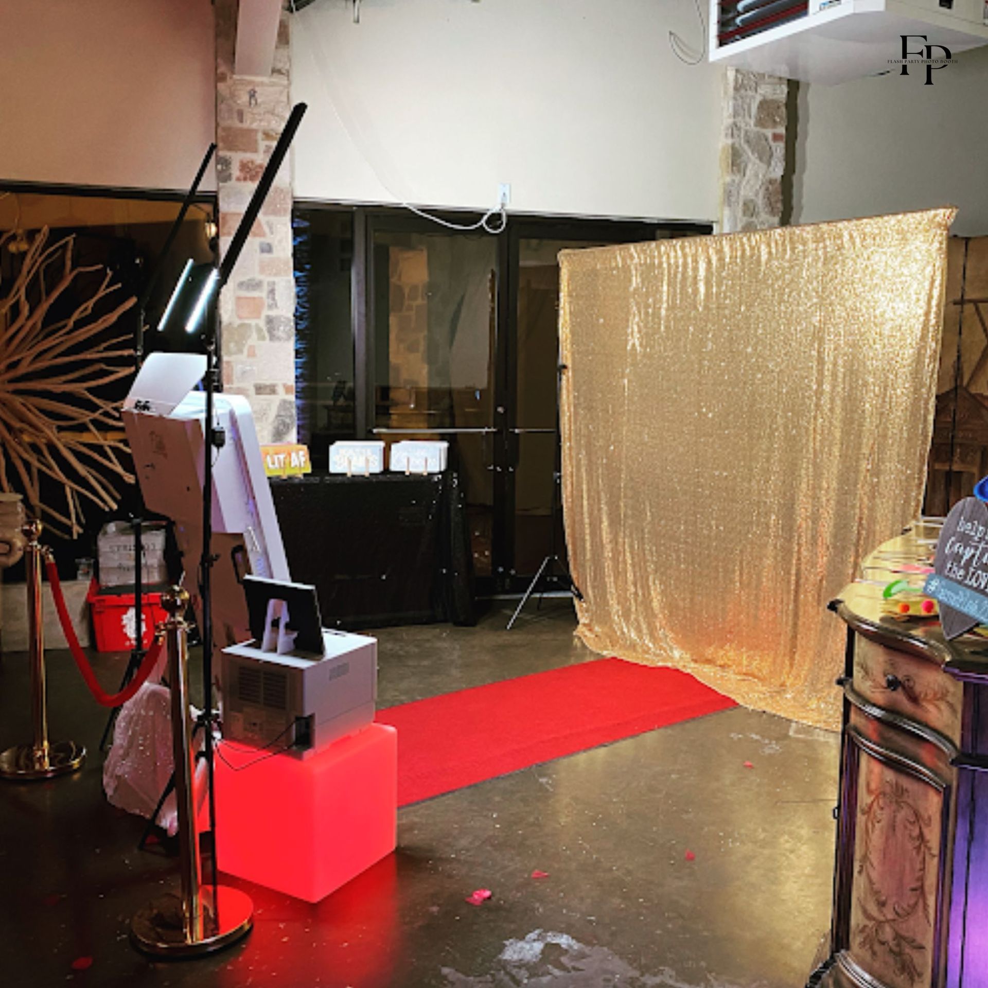 The Mirror Photo Booth set up in a room with a red carpet and a gold curtain backdrop.