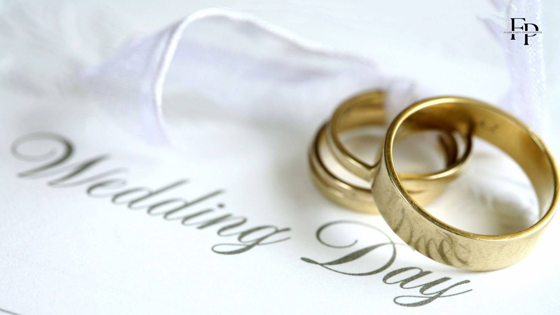 The wedding rings of the bride and the groom on top of the wedding invitation