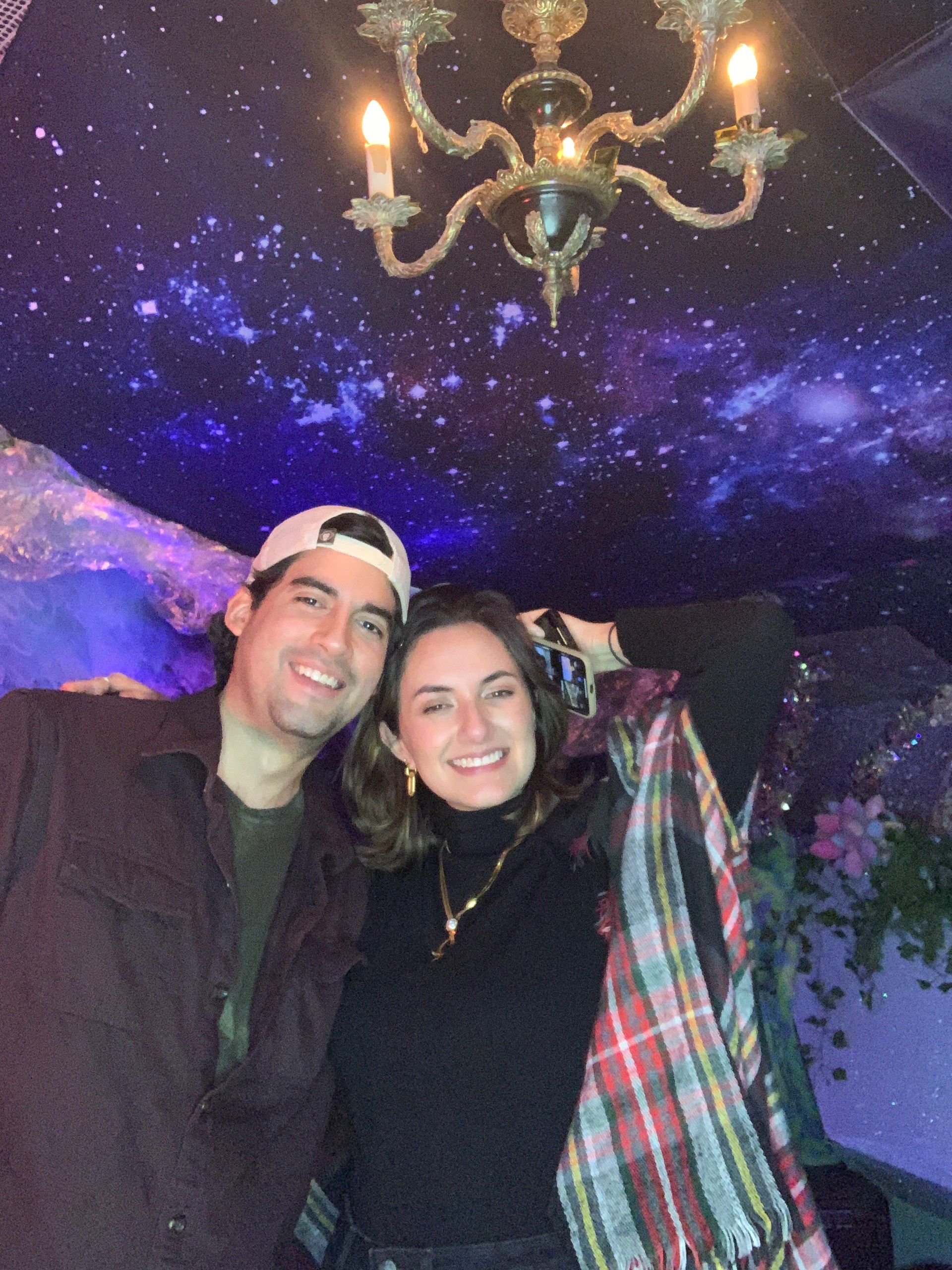 An image of a couple happily posing with the Roamer Photo Booth under a starry ceiling.