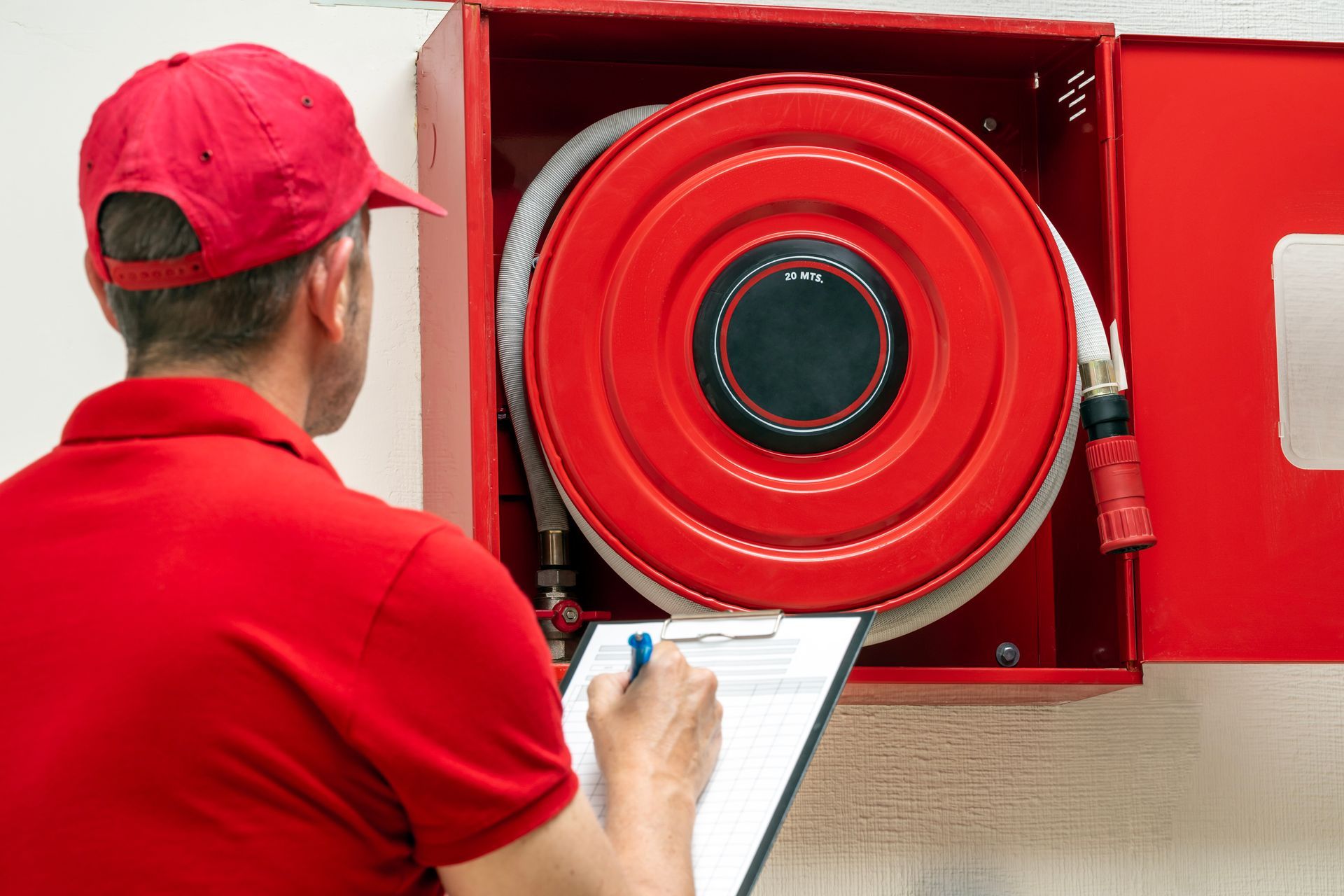 A fire safety technician performing an inspection of a fire hose cabinet.