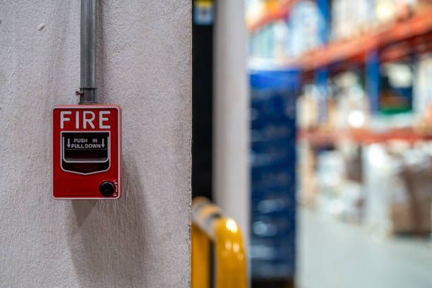 A red fire alarm switch on a concrete wall in an office building