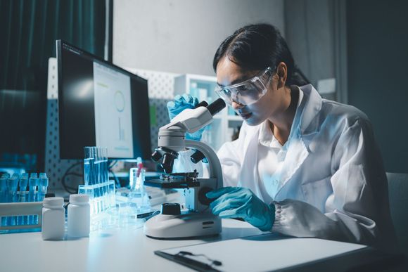 A female scientist is looking through a microscope in a laboratory.