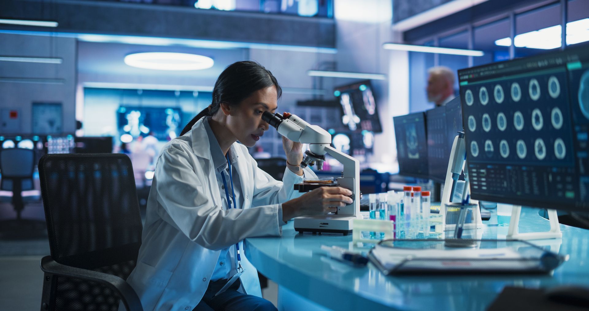 A female scientist is looking through a microscope in a laboratory.