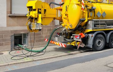 A yellow vacuum truck is parked on the side of the road.