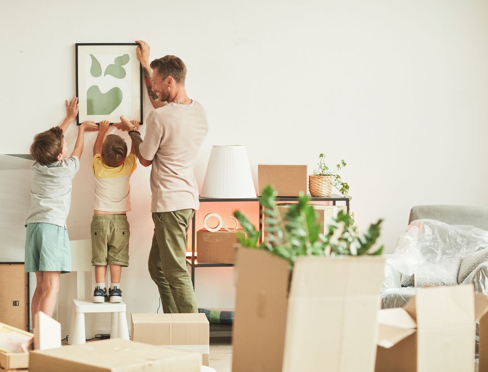 A man and two children are hanging a picture on a wall.
