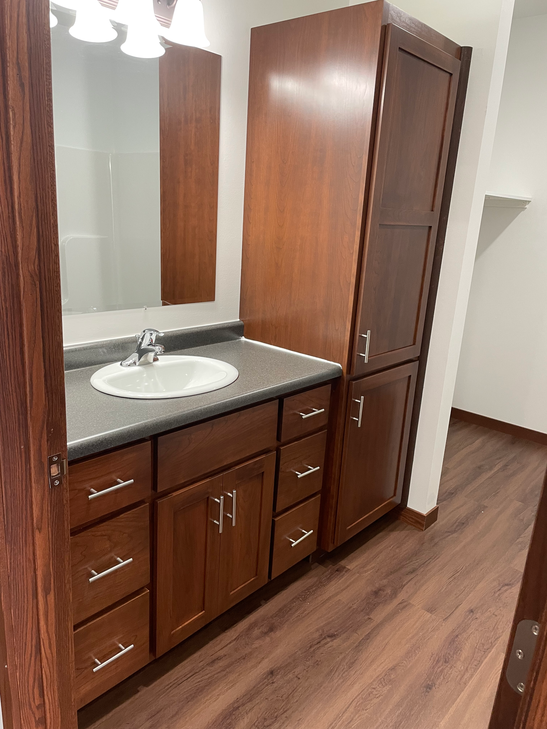 A bathroom with a sink , cabinets , and a mirror.