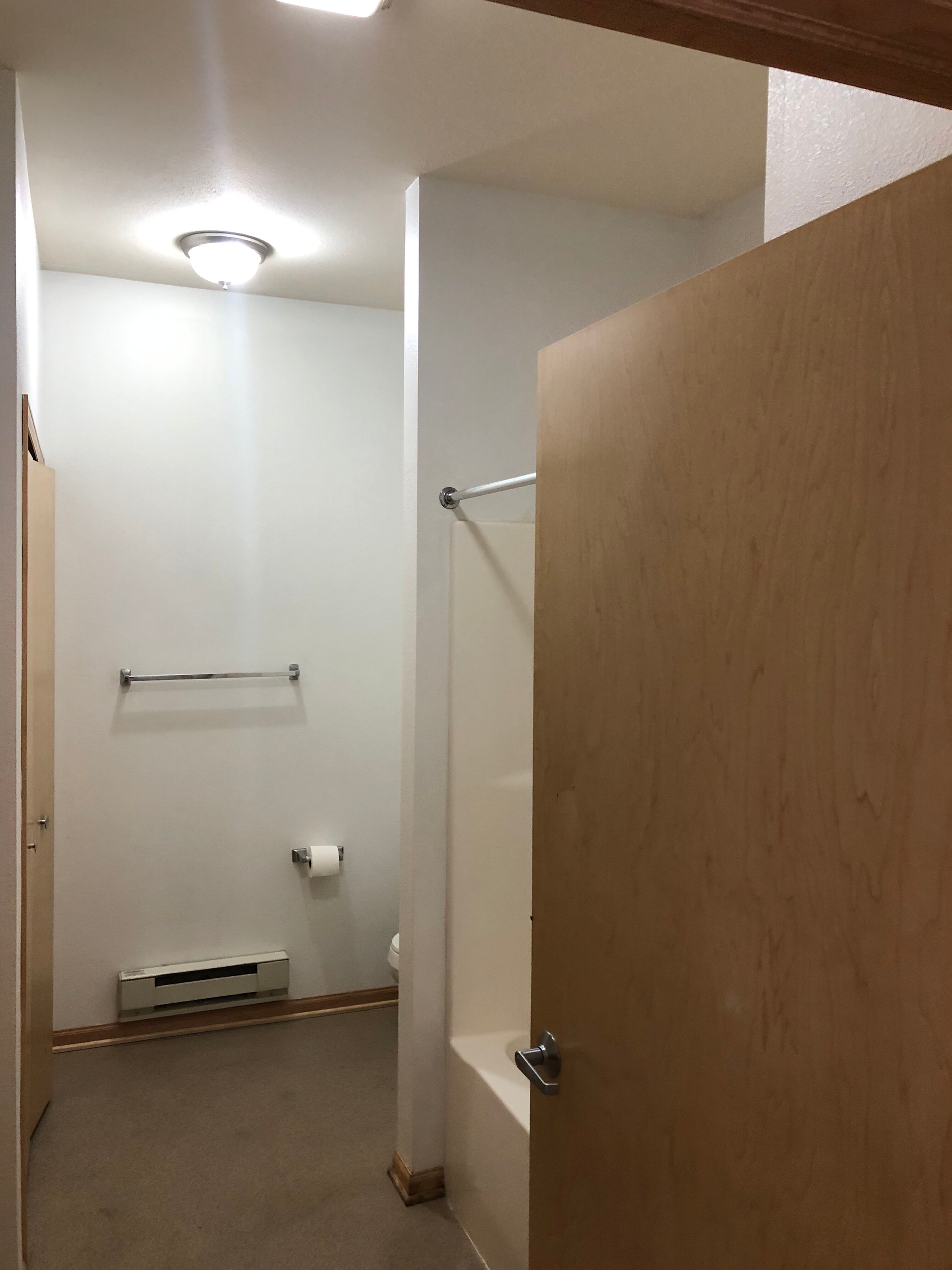 A bathroom with a bathtub , toilet , and towel rack.