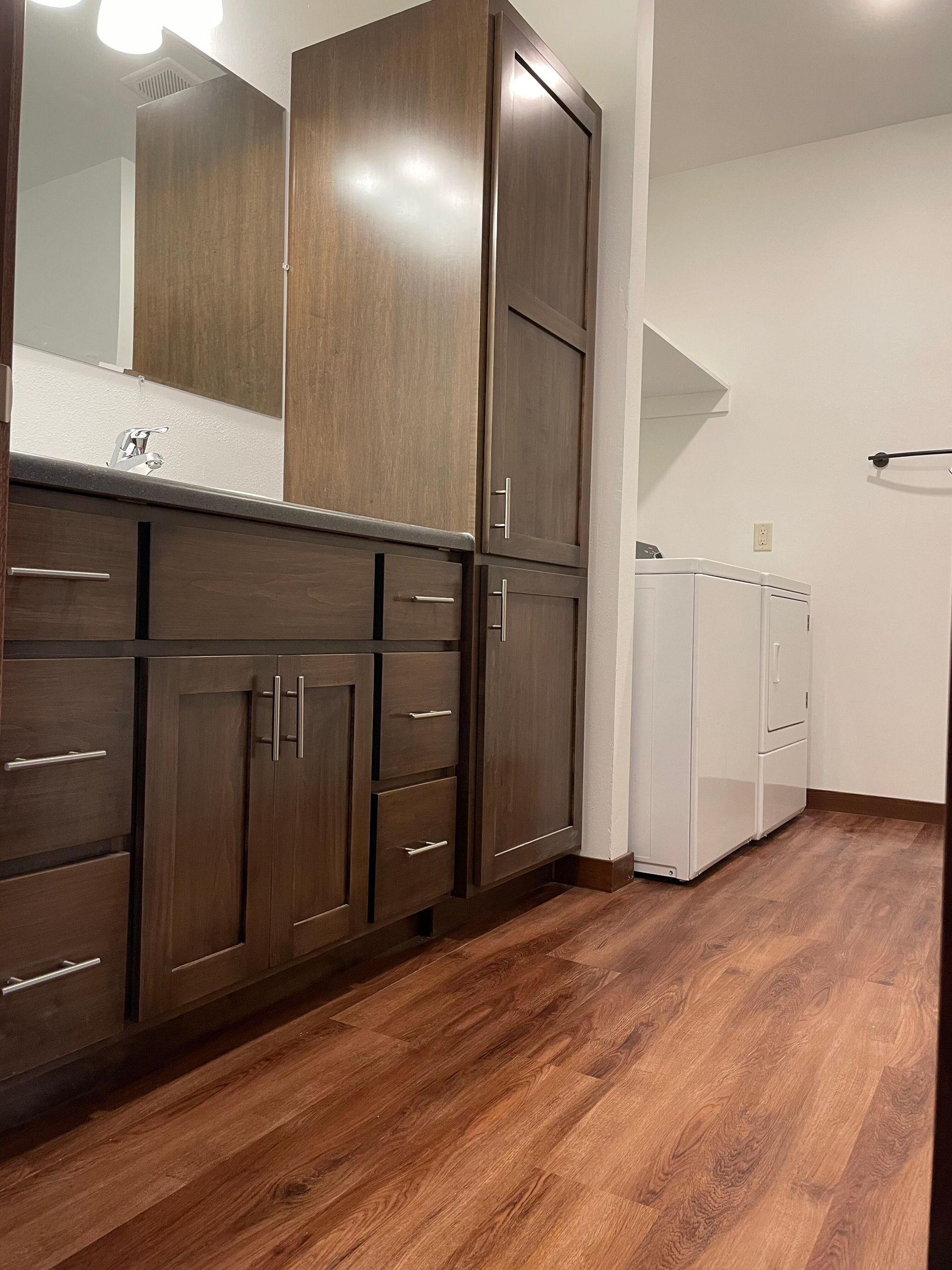 A bathroom with a sink , cabinets , and a washer and dryer.