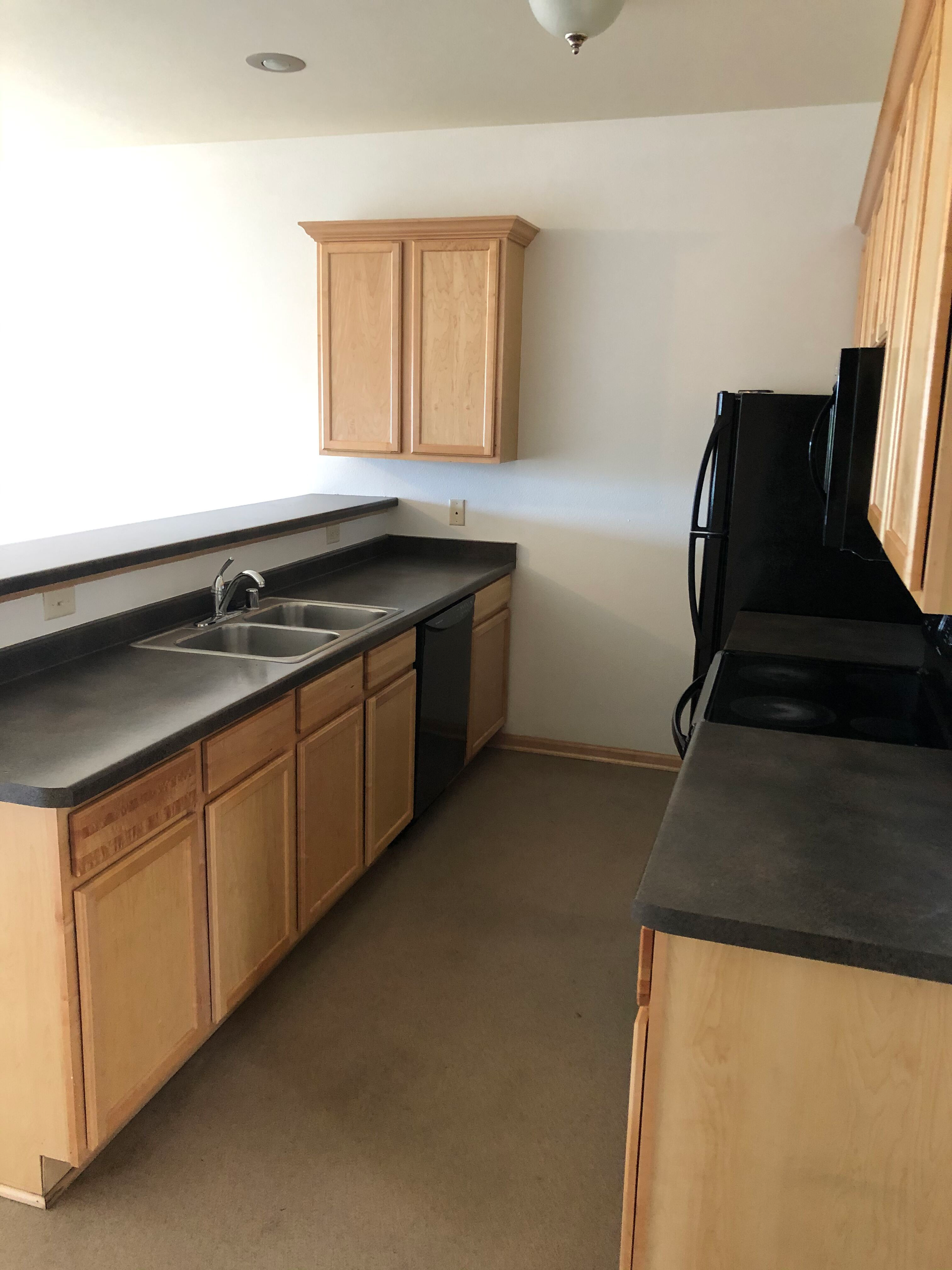 A kitchen with wooden cabinets and black counter tops