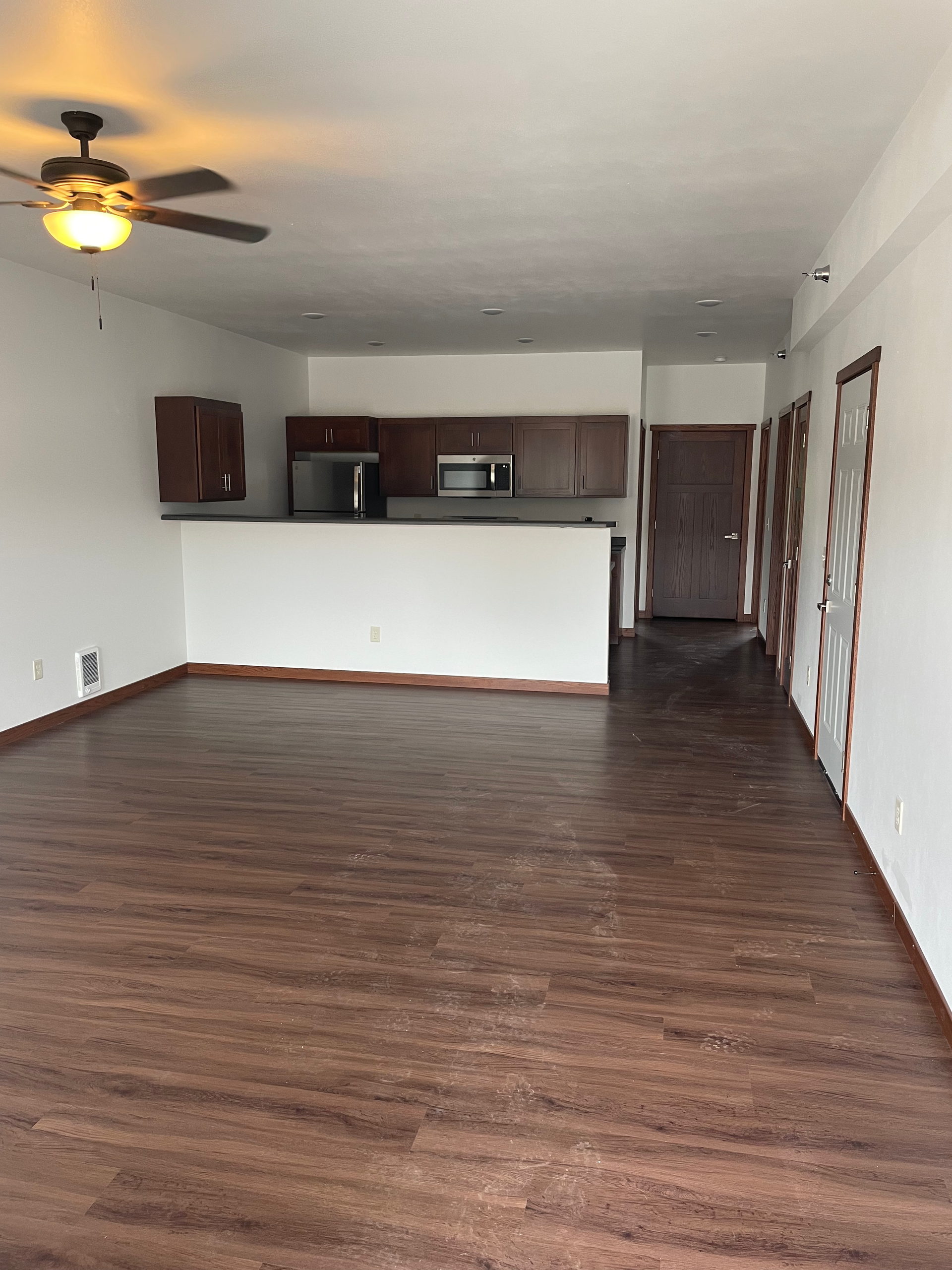 An empty living room with hardwood floors and a ceiling fan.