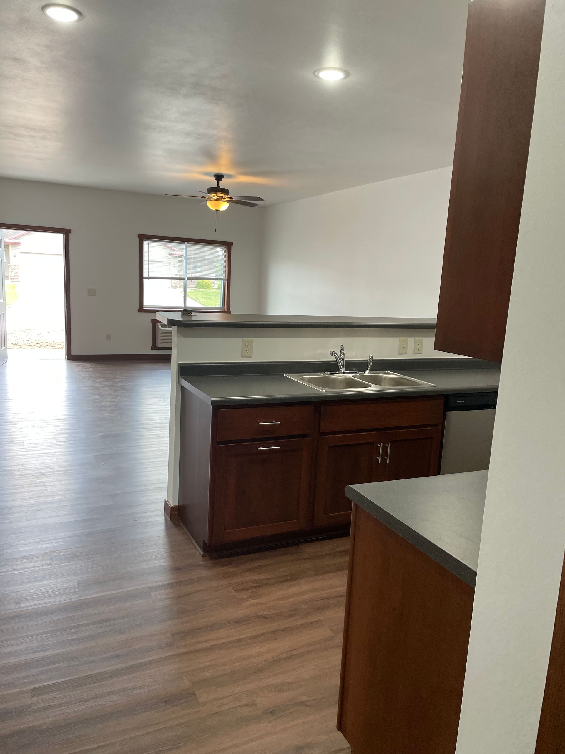 A kitchen with wooden cabinets , a sink , and a ceiling fan.