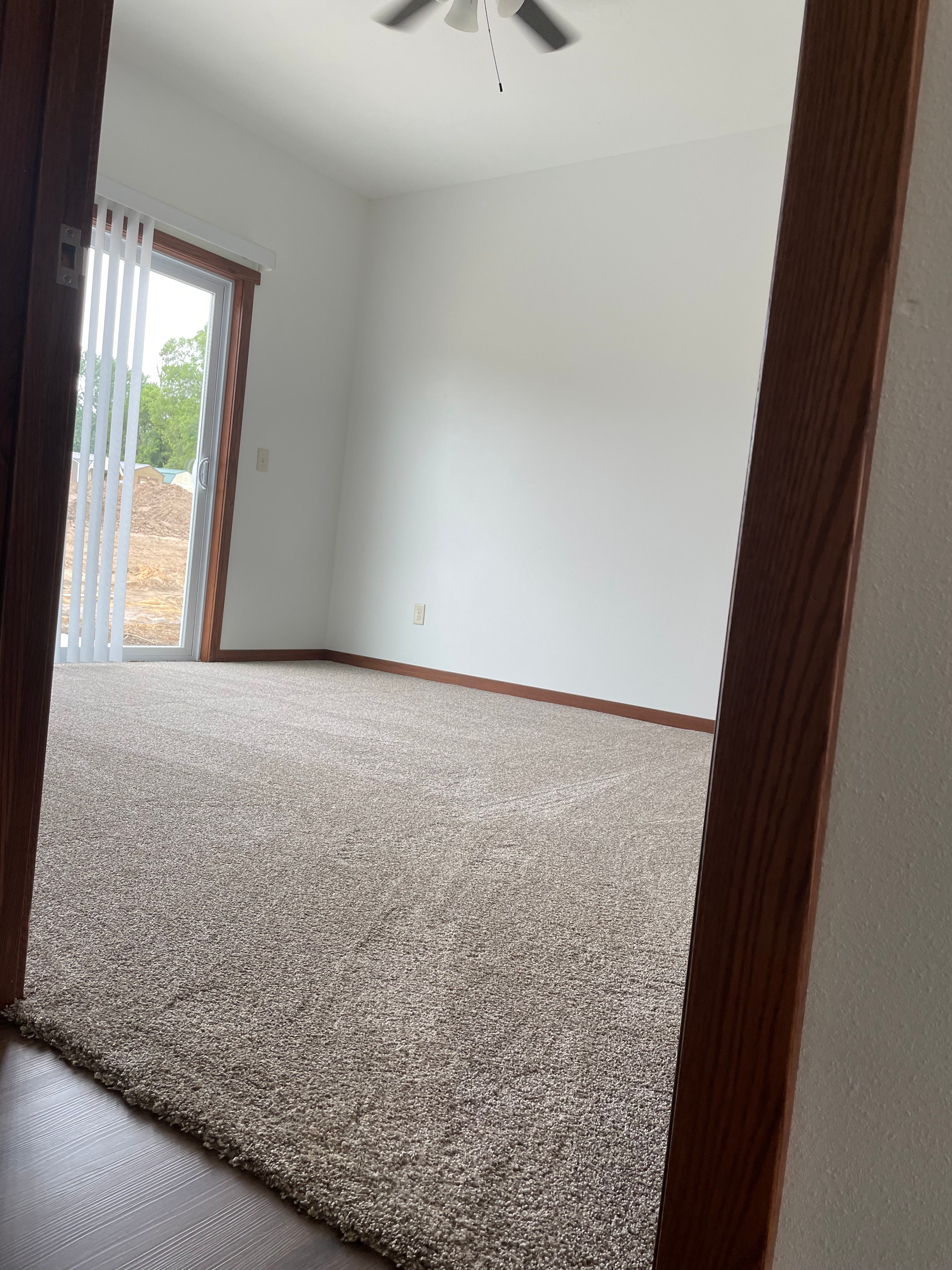 An empty room with a sliding glass door and a ceiling fan