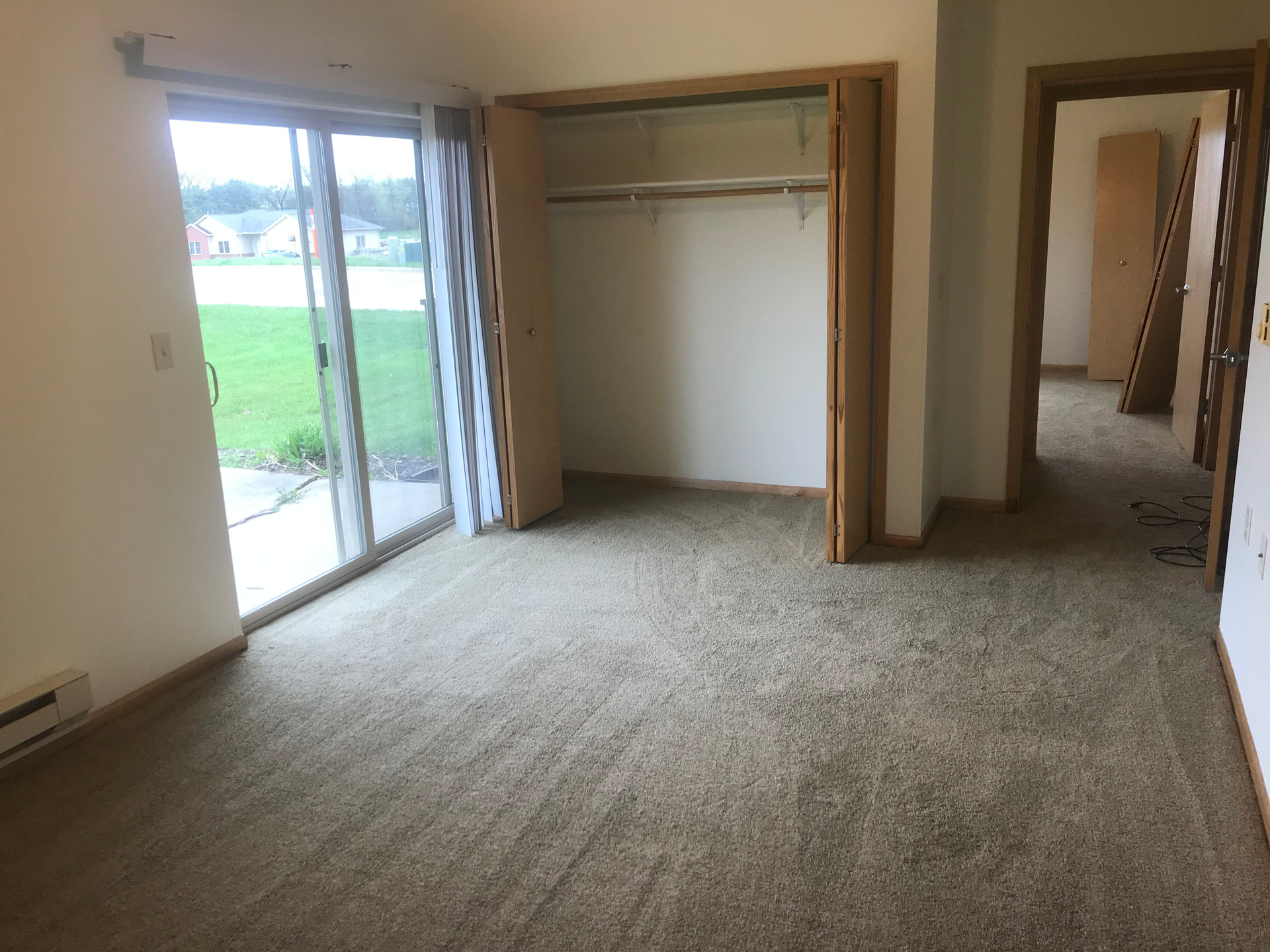 An empty room with a sliding glass door and a closet.