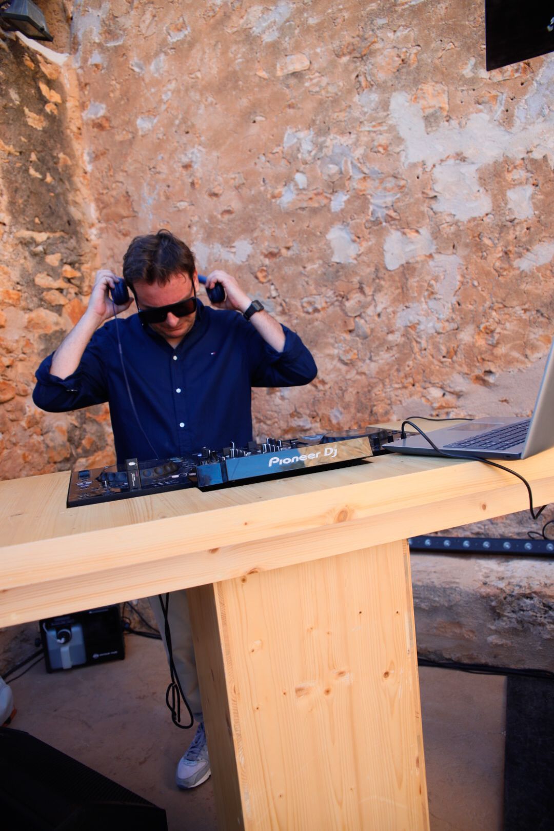 DJ con auriculares y gafas de sol en una fiesta al aire libre. 