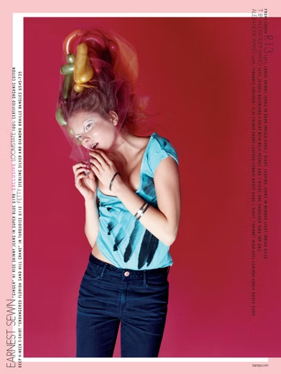 Woman with colorful hair and blue top against a red background.