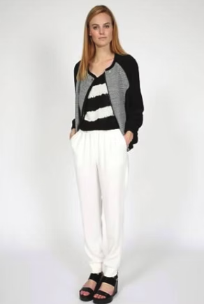 Woman in black and white striped top, gray and black jacket, white pants, and black sandals.