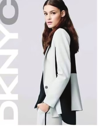 Woman in a color-block blazer and pants, hands in pockets. 