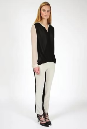 Woman wearing black and cream blouse, cream pants with black side stripe, and black strappy heels.
