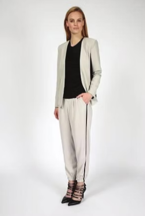 Woman wearing a black top, cream blazer, and pants with black side stripe, with black heels.