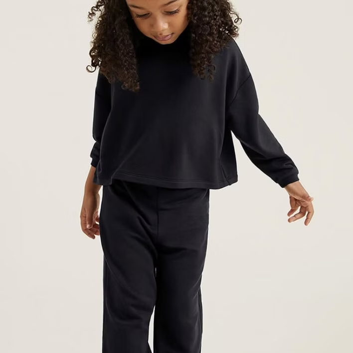 Child wearing a black sweatshirt and pants, looking down.